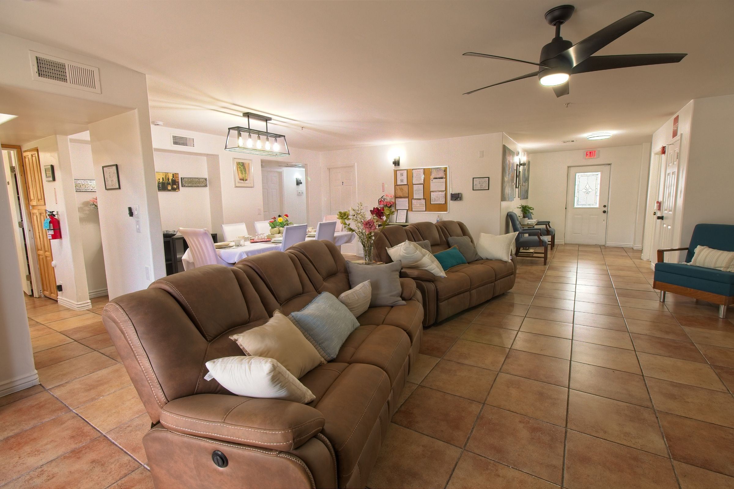The living room, with two brown recliner sofas, a ceiling fan, and the dining room beyond